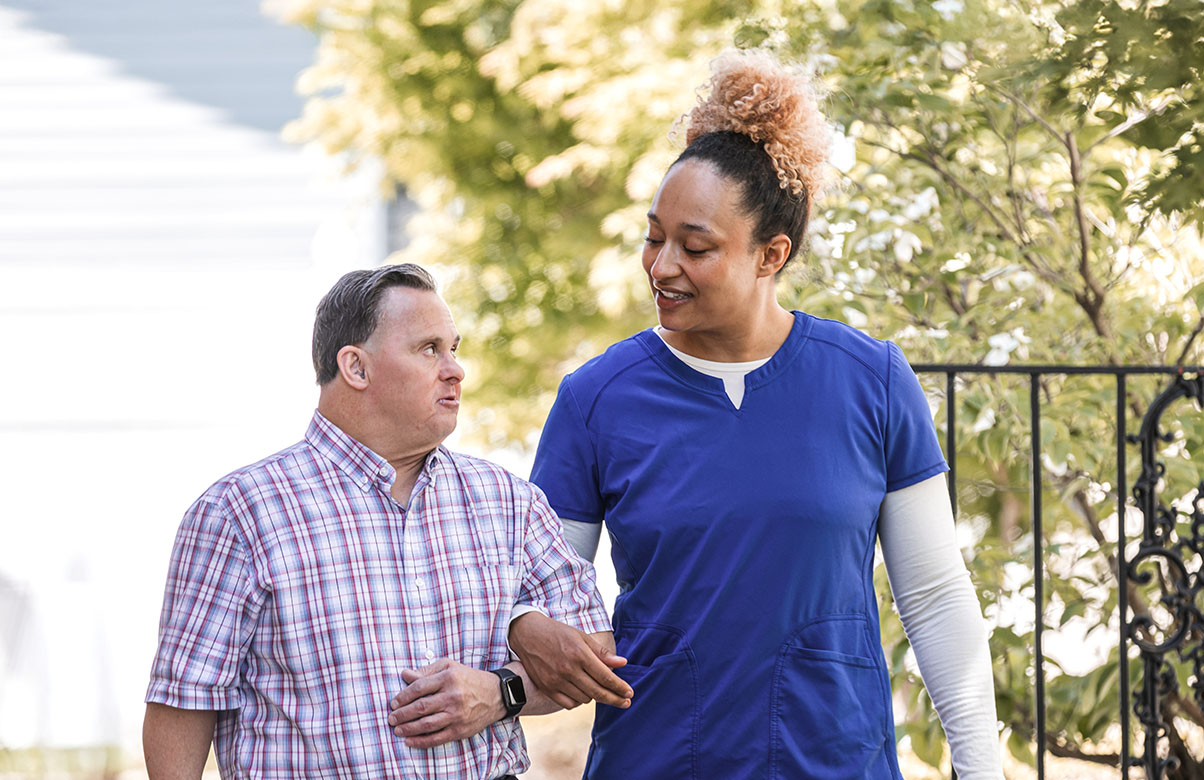 Male patient and female nurse walking outside.