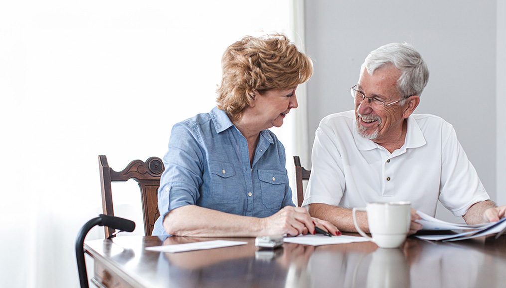 Husband and wife going over paperwork at the dining room table.
