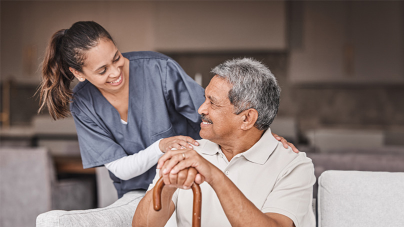 Nurse checking on a man with a cane in his home.