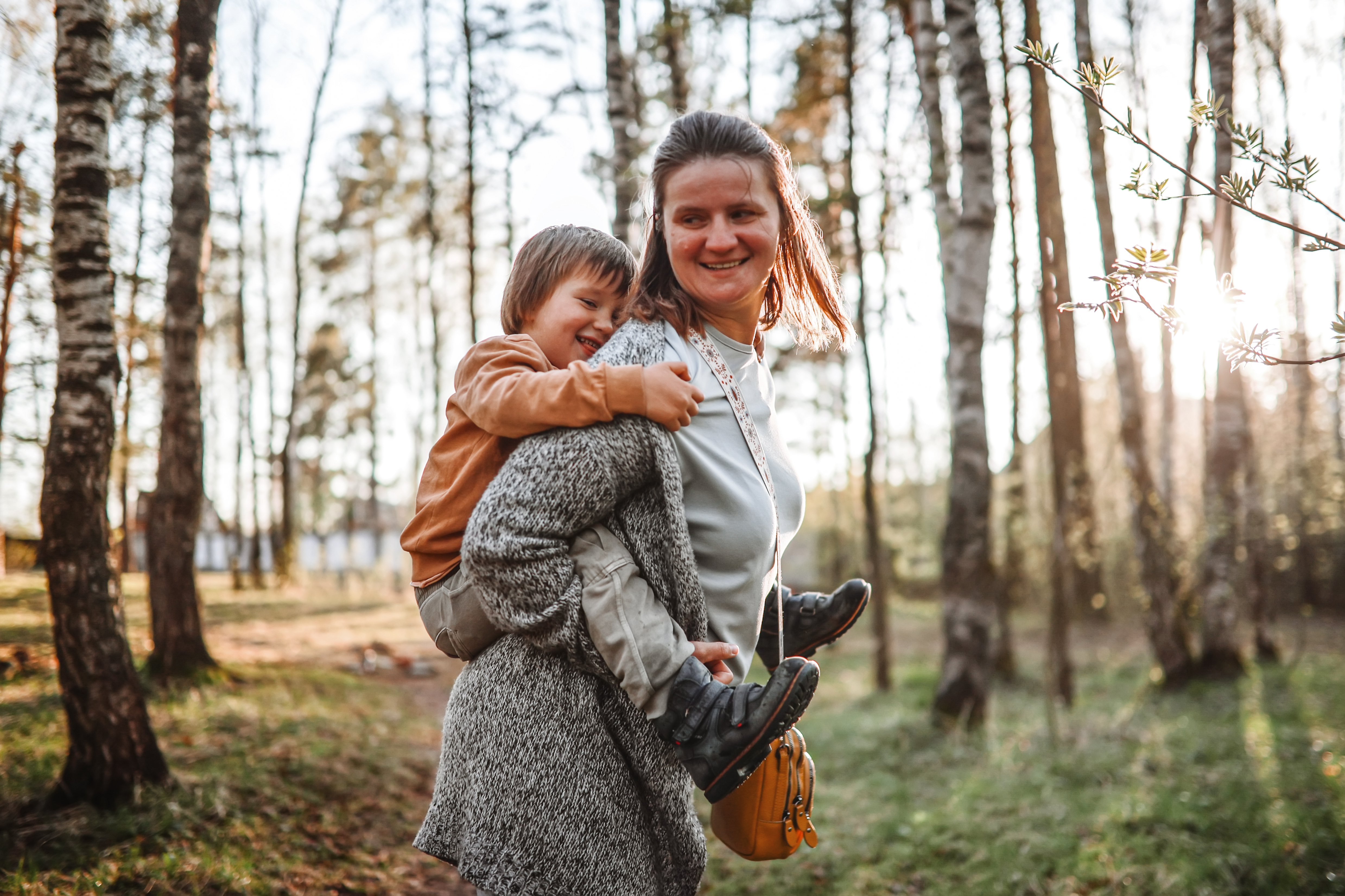 Mother carrying her son on her back through the woods.