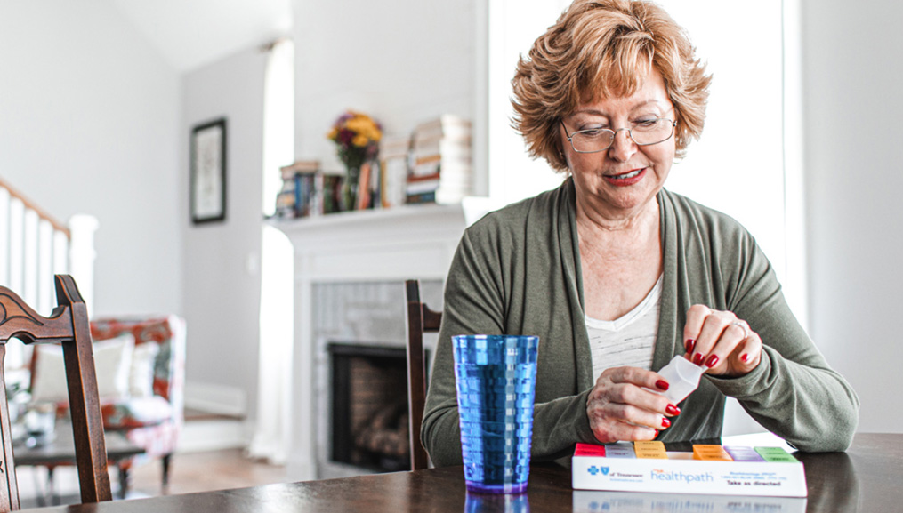 Older woman taking her medication at her dining room table.