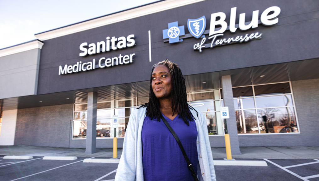 A woman smiling while standing in front of a Blue of Tennessee with Sanitas Medical Center