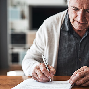 An older man filling out forms.