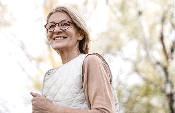 Woman in a vest walking outside.